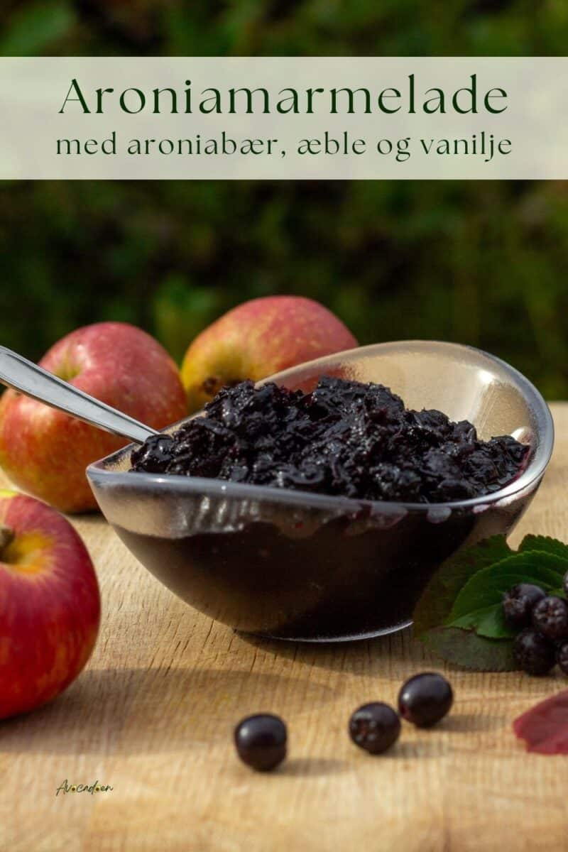 Skål med aroniamarmelade med æble og vanilje med aroniabær i forgrunden og æbler bagved.
