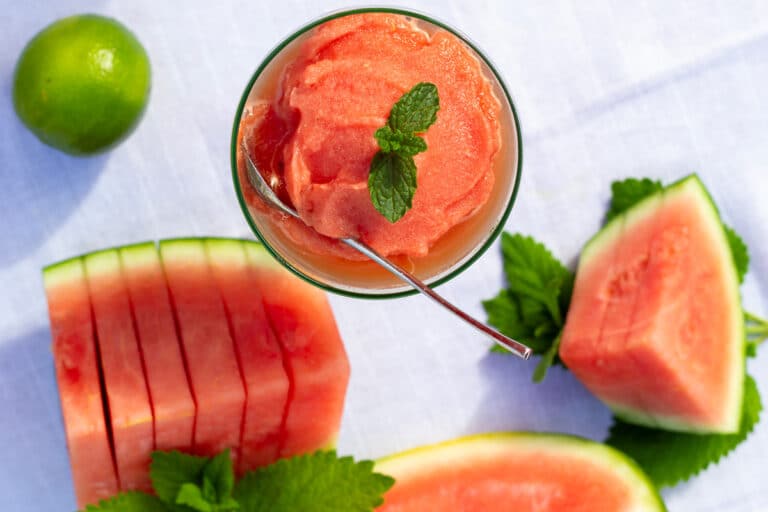 Kold vandmelon‑slushice serveret i glas med mynte, lime og saftige vandmelonstykker – en sommerlig og kølende dessert af frossen vandmelon.
