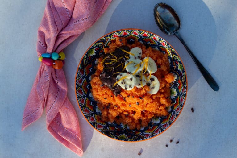 Energigrød med gulerod pyntet med banan, appelsinskal, kakaonibs og nøddecreme