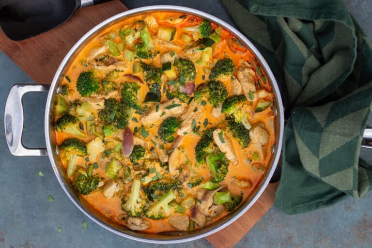 Små stykker kylling i en pande med broccoli, squash og rødløg i flødesovs med paprika og estragon.