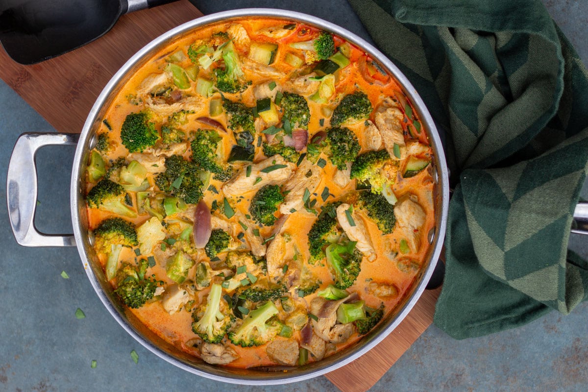 Små stykker kylling i en pande med broccoli, squash og rødløg i flødesovs med paprika og estragon.