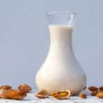 Mandelmælk i en kande omgivet af mandler