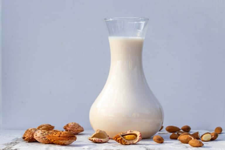 Mandelmælk i en kande omgivet af mandler
