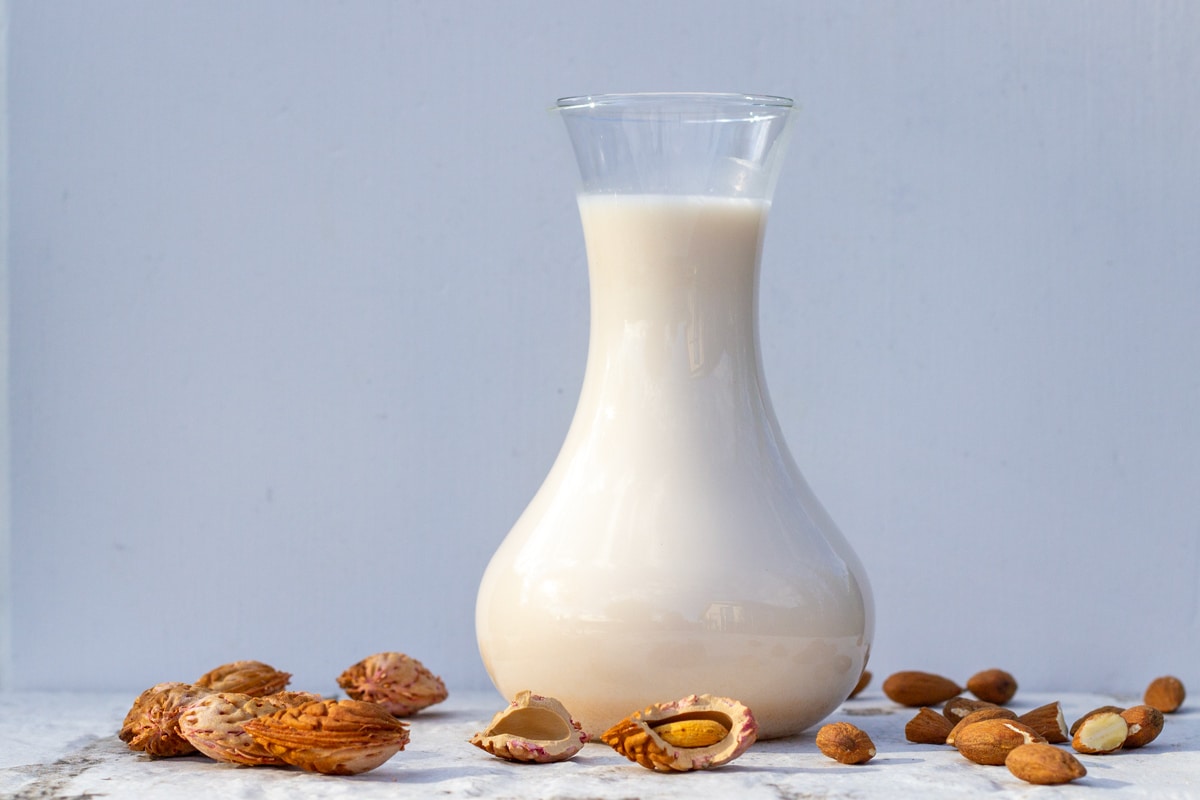 Mandelmælk i en kande omgivet af mandler