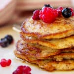 En lille stabel pandekager af mandelmel med sirup, hindbær og blåbær.