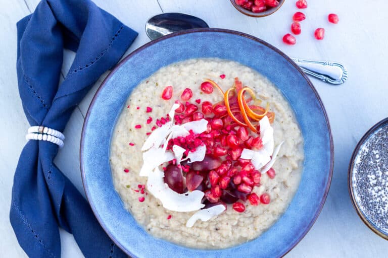Hvid energigrød af blomkål og kikærter. Med kokos og granaæblekerner på toppen.