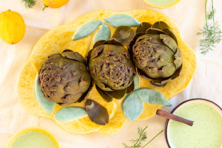 Artiskokker serveret på et fad med green-goddess-dressing til at dyppe bladene i.