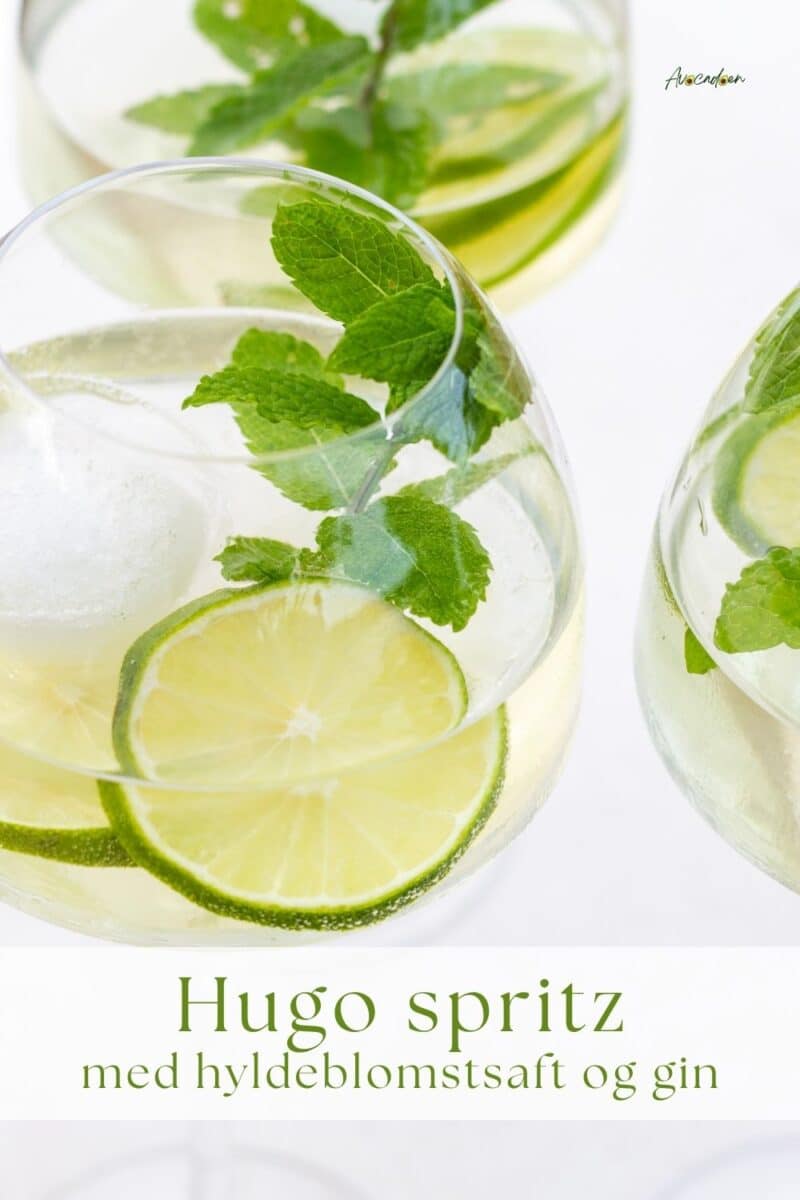 Glas med hugo spritz af hyldeblomstsaft, prosecco, gin og isterninger pyntet med lime og mynte.
