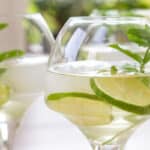 Glas med hugo spritz drink af hyldeblomstsaft, prosecco, gin og isterninger pyntet med lime og mynte.