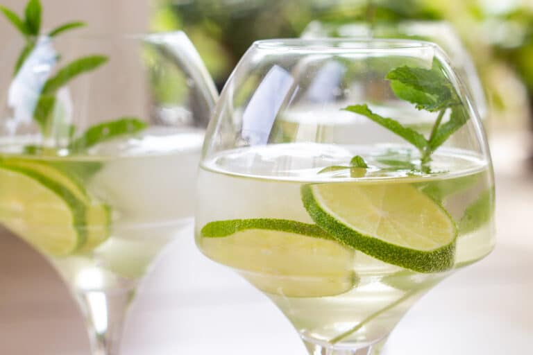 Glas med hugo spritz drink af hyldeblomstsaft, prosecco, gin og isterninger pyntet med lime og mynte.