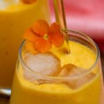 Gul energismoothie med gulerod, appelsin, peberfrugt og kefir pyntet med orange stedmoderblomser